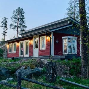 a small red house with a tree in front of it at Vuolenkosken Helmi - laadukas ympärivuotinen kohde in Huutotöyry