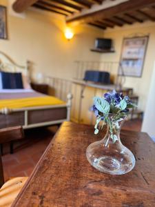 a vase with blue flowers sitting on a wooden table at Pienzalettings "Suites" in Pienza