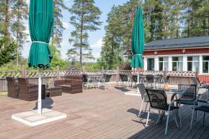 een terras met tafels en stoelen met groene parasols bij Air Hotel Nummela in Nummela