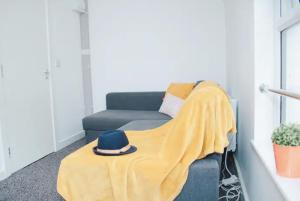 een gele deken op een bank met een hoed erop bij Trendy 2BR Apt near Anfield Stadium in Liverpool