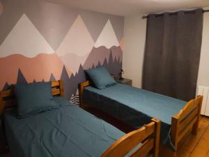 - 2 lits dans une chambre avec des montagnes peintes sur le mur dans l'établissement Appartement Cosy Lac, à Évian-les-Bains