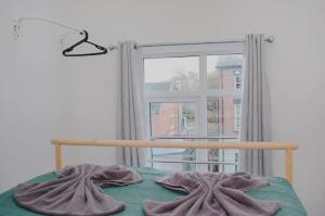 een slaapkamer met een bed en een raam met een deken bij Trendy 2BR Apt near Anfield Stadium in Liverpool