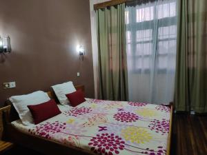 a bedroom with a bed with a floral bedspread at Hôtel Diamant Antsirabe in Antsirabe