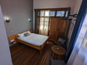 a small bedroom with a bed and a chair at Hôtel Diamant Antsirabe in Antsirabe
