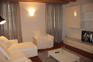 sala de estar con 2 sillas blancas y TV en [Centro storico] deluxe flat, en Udine