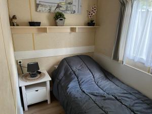 a small bedroom with a bed and a table with a lamp at La caravane de Maminou in Stavelot