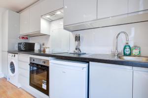 a white kitchen with white cabinets and a sink at Gorgeous 1 Bedroom Property in London
