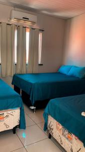 twee bedden in een kamer met blauwe lakens bij Pousada Brandão in Parnaíba