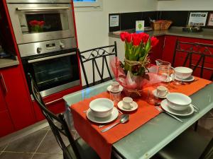 una mesa de cocina con un jarrón de flores rojas. en Appartement de 3 chambres avec piscine partagee jardin clos et wifi a Maurens, en Maurens