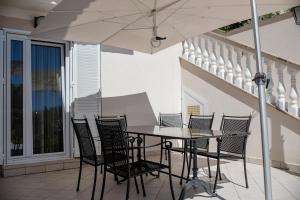 a table and chairs with an umbrella on a patio at Spacious modern One bedroom Apartment with Garden & SeaView in Rab