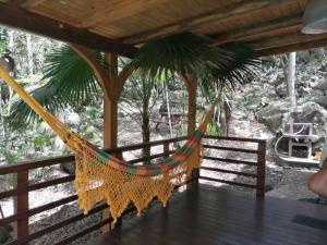 a hammock on a wooden porch with a tree at CHALET & MAISONS BULLES Deluxe in Bouillante