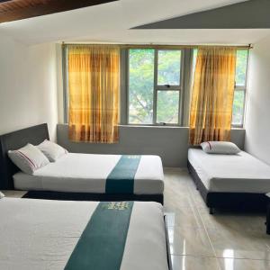 1 dormitorio con 2 camas y 2 ventanas en Hotel Casa Botero Medellín RNT 152104 en Medellín
