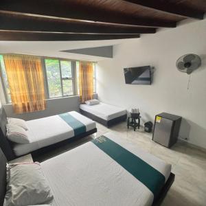 1 dormitorio con 2 camas y TV. en Hotel Casa Botero Medellín RNT 152104 en Medellín