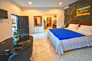 a large bedroom with a blue bed and a table at Serendipity Bali in Sanur