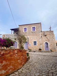 une maison en pierre avec des portes violettes sur un mur en pierre dans l'établissement Iliana's house - spacious cave house in the center of Areopolis, à Areópoli