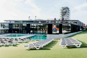 a group of white lounge chairs and a swimming pool at Vakantiehuis The Nuthouse in Roeselare