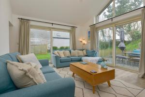 a living room with blue couches and a table at Kelmscot in Port Isaac