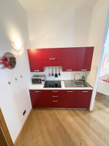 a kitchen with red cabinets and a sink at Monolocale sulle piste da sci in Pila