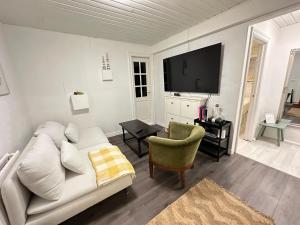 ein Wohnzimmer mit einem weißen Sofa und einem TV in der Unterkunft Apartment in Reykjavikurvegur - Birta Rentals in Hafnarfjördur