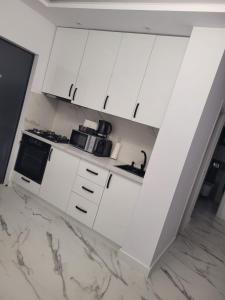 una cocina blanca con armarios y electrodomésticos blancos en TAG Apartament, en Timisoara