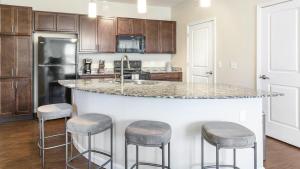 uma cozinha com uma grande ilha com bancos de bar em Landing - Modern Apartment with Amazing Amenities (ID1196X495) em Fishers