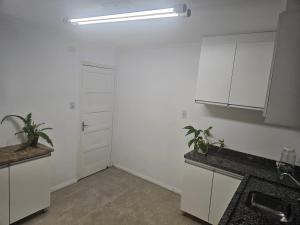 uma cozinha com armários brancos e dois vasos de plantas em Espaço Semente Poa Lírio em Porto Alegre