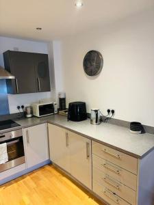 a kitchen with white cabinets and a clock on the wall at Play Away Lodge in Basildon