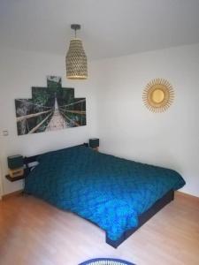 um quarto com uma cama azul e uma fotografia na parede em Chez Léo & Julie em Caen