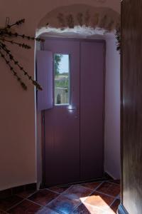 a purple door in a room with a window at Iliana's house - spacious cave house in the center of Areopolis in Areopolis