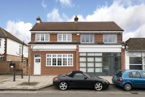 een zwarte auto en een blauwe auto geparkeerd voor een huis bij London House in Londen