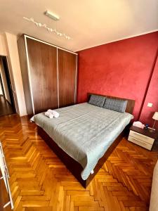 Bett in einem Zimmer mit roter Wand in der Unterkunft Amy's Bright Apartment in Constanţa