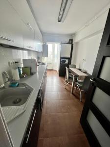 eine Küche mit einem Waschbecken und einem Tisch darin in der Unterkunft Amy's Bright Apartment in Constanţa