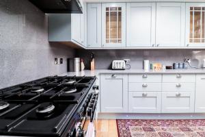 a kitchen with white cabinets and a black stove at Luxurious 5 Bed Property! in Woodley