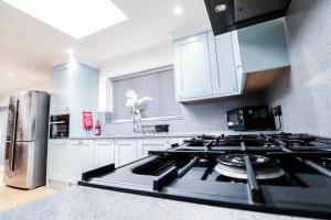 uma cozinha com uma placa de fogão e forno. em Luxurious 5 Bed Property! em Woodley