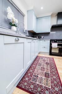 a kitchen with white cabinets and a rug on the floor at Luxurious 5 Bed Property! in Woodley