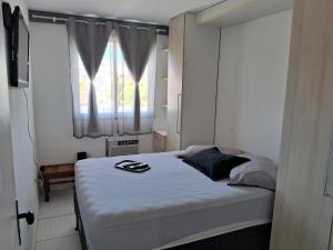1 dormitorio con cama y ventana en Solar do Pontal - Lindo Apartamento a 600m da praia, en Río de Janeiro
