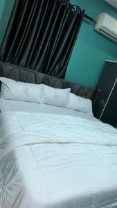 un grande letto con lenzuola e cuscini bianchi di TM Royal Hotel, Ibadan a Ibadan