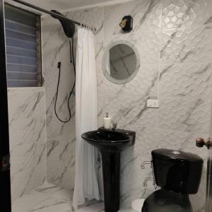 a bathroom with a black toilet and a sink at Stylish studio apartment in Quito