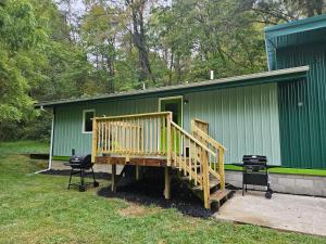 a green building with a wooden ramp leading to a house at Frog Hollow at Hocking Vacations in Logan