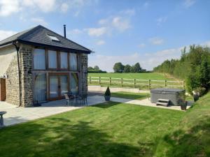 a stone cottage with a grill and a lawn at 1 Bed in Dulverton 59339 in Knowstone