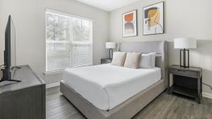 um quarto branco com uma cama e uma televisão em Landing - Modern Apartment with Amazing Amenities (ID1375X557) em Wake Forest