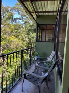 balcón con sillas y vistas al bosque en Cabañas La Montaña Mountain Lodge, en Monteverde