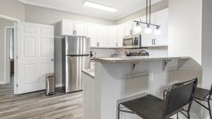 La cuisine est équipée de placards blancs et d'un réfrigérateur en acier inoxydable. dans l'établissement Landing - Modern Apartment with Amazing Amenities (ID7327X28), à Wake Forest
