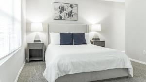 ein weißes Schlafzimmer mit einem Bett mit blauen Kissen in der Unterkunft Landing - Modern Apartment with Amazing Amenities (ID9232X12) in Forest Park