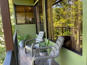 dos sillas blancas sentadas en un porche cerrado en Cabañas La Montaña Mountain Lodge, en Monteverde