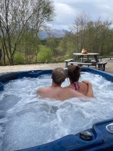 a man and a woman sitting in a hot tub at Camden House luxury home near Ben Nevis Scotland Highlands in Fort William