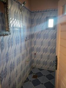 a bathroom with a shower with blue and white tiles at Nomad Bivouac in Merzouga