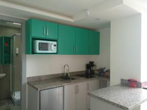 a kitchen with green cabinets and a microwave at Perfect Suite, near everything! ¡cerca de todo! in Quito