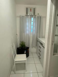 een witte kamer met een stoel en een raam bij Caminho das Pedras Búzios in Búzios