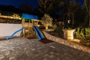 um parque infantil com escorrega num quintal à noite em Vila Petram em Bribir